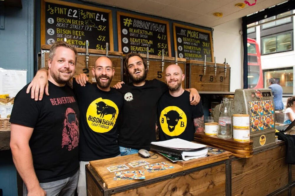 Bison Beer staf smiling and embracing behind a counter.