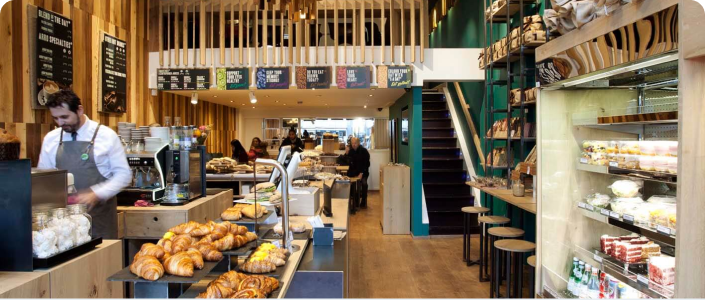 Interior of Arro Coffee House showing a fully stucked display shelf, a busy counter and display case.