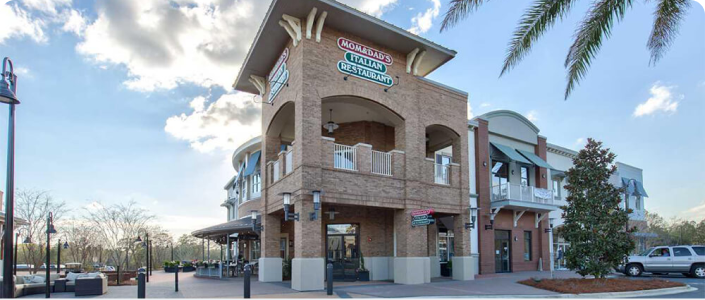 A two-story building with large arches and brick façade, housing Mom & Dad's Italian restaurant, set against a sunny sky.